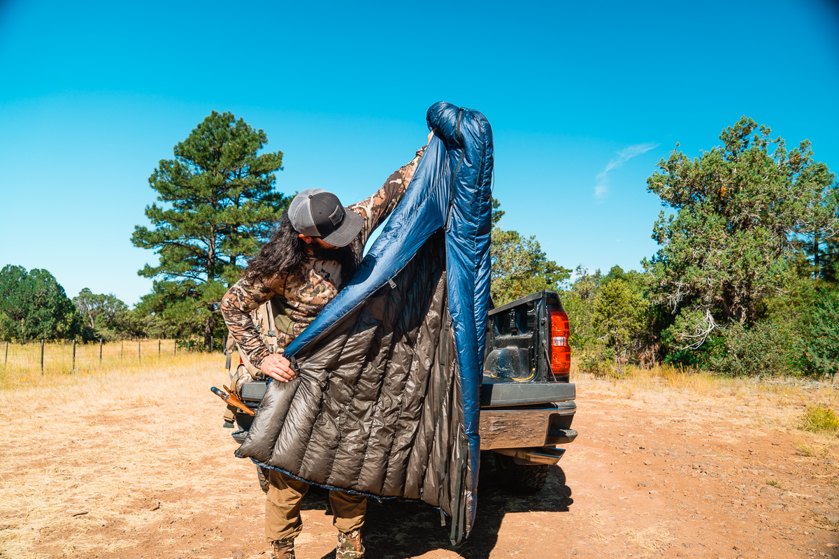 Josh Kirchner from Dialed in Hunter holding up his quilt for backcountry hunting